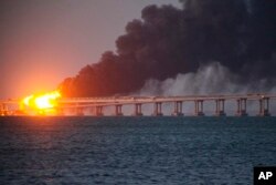 Flame and smoke rise from the Crimean bridge connecting the Russian mainland and the Crimean peninsula over the Kerch Strait, in Kerch, Crimea, Oct. 8, 2022.