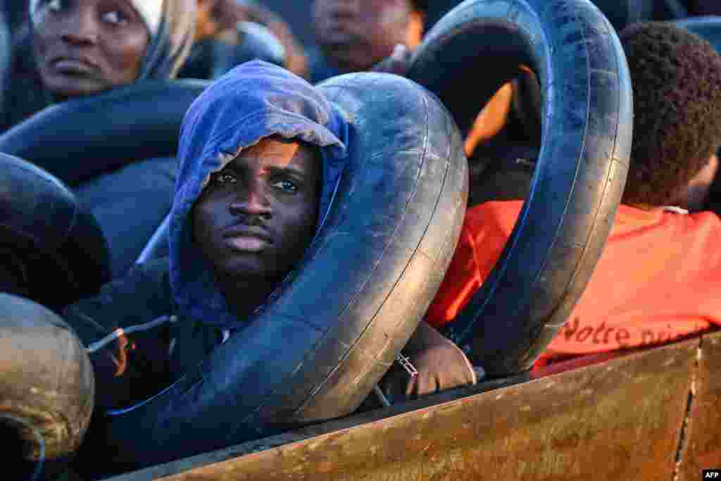 Migrants from sub-Saharan Africa sit in a makeshift boat that was being used to clandestinely make its way towards the Italian coast, as they are found by Tunisian authorities about 50 nautical miles in the Mediterranean Sea off the coast of Tunisia&#39;s central city of Sfax.
