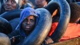 Migrants from sub-Saharan Africa sit in a makeshift boat that was being used to clandestinely make its way towards the Italian coast, as they are found by Tunisian authorities about 50 nautical miles in the Mediterranean Sea off the coast of Tunisia's cen