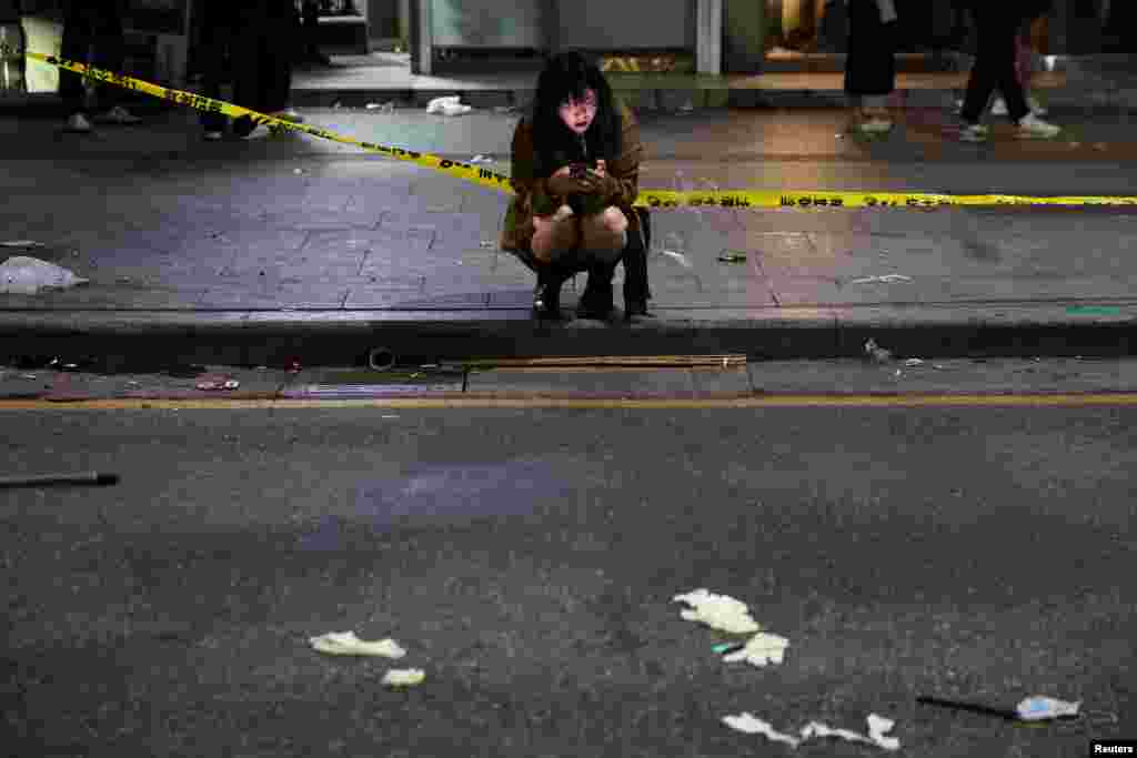 A woman uses a phone near the scene where many people died and were injured in a stampede during a Halloween festival in Seoul, South Korea, Oct. 30, 2022.