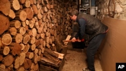 Tudor Popescu chops fire wood he uses for heating in a storage room attached to his home in Chisinau, Moldova, Saturday, Oct. 15, 2022. (AP Photo/Aurel Obreja)