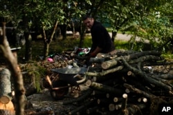 Viktor Palyanitsa piles freshly cut logs in the yard of his house in Kurylivka, Ukraine, Sunday, Oct. 16, 2022. (AP Photo/Francisco Seco)