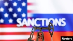 A model of a pump jack is seen in front of the displayed word "Sanctions;" U.S. and Russian flag colors in this illustration taken March 8, 2022. (Dado Ruvic/REUTERS)