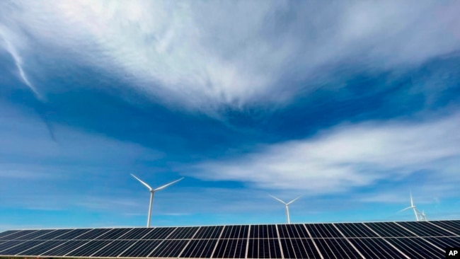 In this image provided by Portland General Electric, windmills and solar panels line a renewable energy facility in Lexington, Ore., on this May 24, 2022. The facility combines solar power, wind power and massive batteries to store the energy generated th