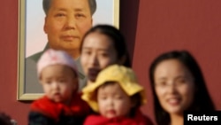 FILE - Two women and their babies pose for photographs in front of the giant portrait of late Chinese chairman Mao Zedong on the Tiananmen Gate in Beijing Nov. 2, 2015.