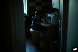 Artem Panchenko eats a meal in the apartment where he lives with his grandmother Iryna in Kivsharivka, Ukraine, Sunday, Oct. 16, 2022. (AP Photo/Francisco Seco)