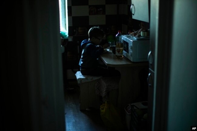 Artem Panchenko eats a meal in the apartment where he lives with his grandmother Iryna in Kivsharivka, Ukraine, Sunday, Oct. 16, 2022. (AP Photo/Francisco Seco)