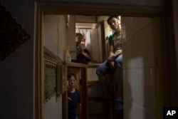 FILE - Residents pose in their tiny "shoebox" apartments, in Hong Kong, May 4, 2017.