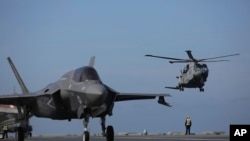 FILE - Military personnel direct F-35 jets and a helicopter on the deck of the aircraft carrier HMS Queen Elizabeth as it participates in the NATO Steadfast Defender 2021 exercise off the coast of Portugal, May 27, 2021.
