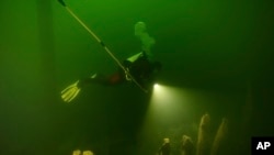 In this undated photo a diver swims by the wreck of a ship in the waters off Vaxholm, Sweden.