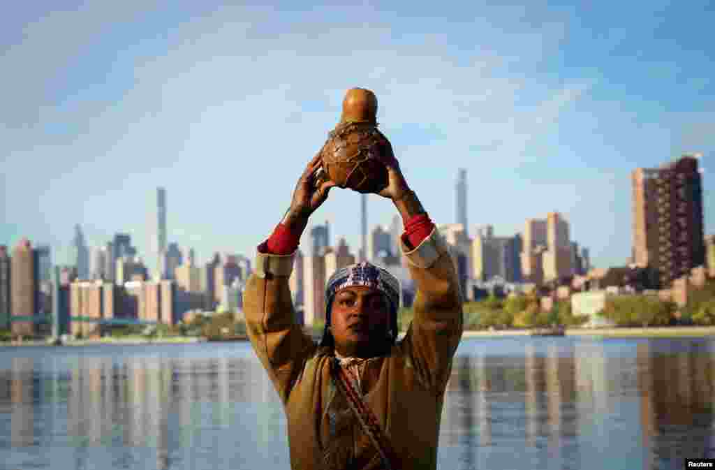 Chenae Bullock of The Shinnecock Indian Nation holds a traditional container of water during an indigenous sunrise water ceremony on the shore of the East River on Randall&#39;s Island in New York City as Indigenous Peoples&#39; Day is observed in the U.S.