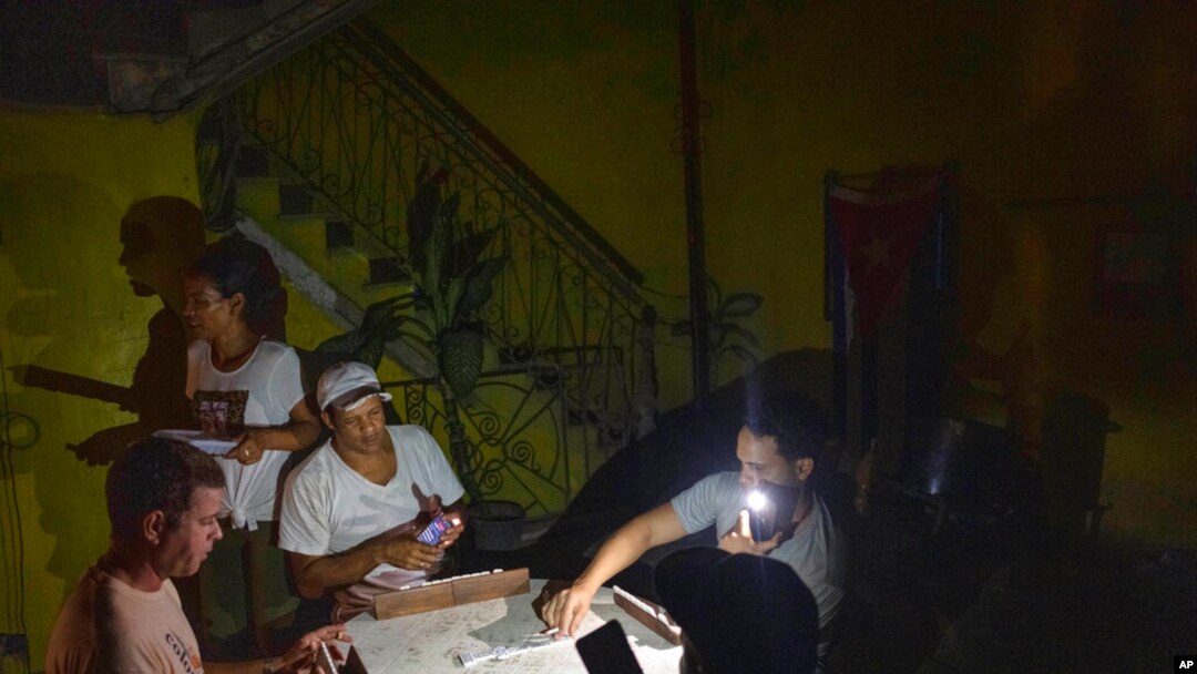Warga Kuba bermain domino dengan senter saat listrik padam pasca badai Ian di ibu kota Havana, Rabu, 28 September 2022.