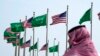 FILE - A man stands under U.S. and Saudi Arabian flags prior to a visit by President Joe Biden, at a square in Jeddah, Saudi Arabia, July 14, 2022. 