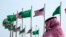 FILE - A man stands under U.S. and Saudi Arabian flags prior to a visit by President Joe Biden, at a square in Jeddah, Saudi Arabia, July 14, 2022. 