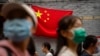 People walk past a Chinese flag on a tourist shopping street on the first day of the National Day holiday period in Beijing, Oct. 1, 2022. 