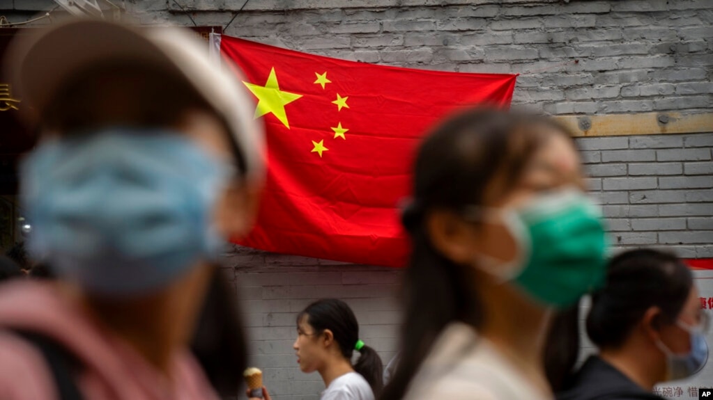 2022年10月1日，北京国庆假期的第一天，人们走在悬挂中国国旗的一条旅游购物街上。(photo:VOA)