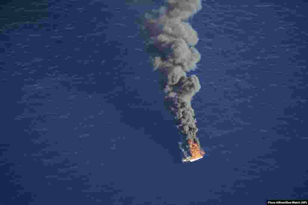 In this handout photo released by German non-governmental organization Sea-Watch, Oct. 25, 2022, an empty rubber boat used by migrants attempting to cross the Mediterranean Sea to Europe is seen on fire after being intercepted by a Libyan coast guard ship in international waters.