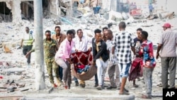 Rescuers and volunteers remove a seriously-injured victim from the scene of a double car-bomb attack in Somalia's capital Mogadishu, Oct. 29, 2022.