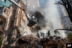 Firefighters work after a drone attack on buildings in Kyiv, Oct. 17, 2022. Waves of explosive-laden suicide drones struck Ukraine's capital as families were preparing to start their week early Monday, the blasts echoing across Kyiv.