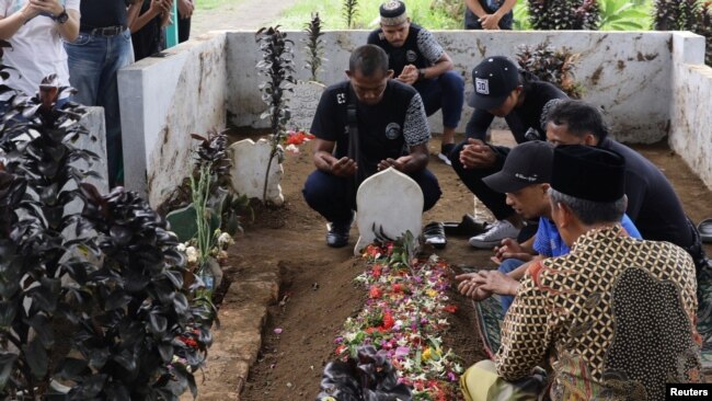 Los jugadores y funcionarios del Arema FC rezan ante las tumbas de las víctimas que murieron durante un motín y una estampida después de un partido de fútbol entre Arema y Persebaya en el estadio Kanjuruhan en Malang, provincia de Java Oriental, Indonesia, el 3 de octubre de 2022, en esta foto tomada por Antara Foto. Antara Foto/H Prabowo/vía REUTERS