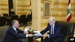 El primer ministro de Líbano, Najib Makati, a la derecha, recibe el borrador final del acuerdo de fronteras marítimas entre Líbano e Israel de manos de su número dos, Elias Bou Saab, que lidera el equipo negociador libanés, en Beirut, Líbano, el martes 11 de octubre de 2022. 