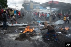 Demonstran berkerumun di sekitar barikade yang didirikan untuk memprotes kenaikan harga bahan bakar dan menuntut Perdana Menteri Haiti Ariel Henry mundur, di Port-au-Prince, Haiti, Senin, 19 September 2022. (Foto: AP)