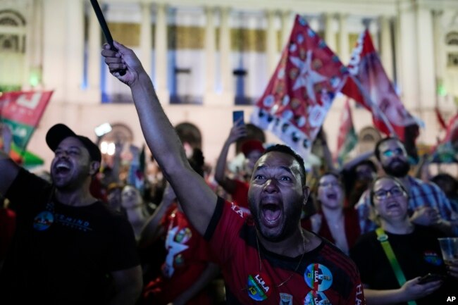 Followers of former Brazilian President Luiz Inacio Lula da Silva, who is running for president again, react to partial results after general election polls closed in Rio de Janeiro, Brazil, Sunday, Oct. 2, 2022. (AP Photo/Silvia Izquierdo)