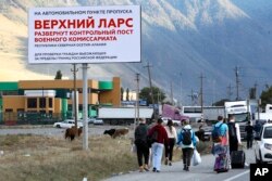 People walk toward the border crossing at Verkhny Lars between Georgia, and Russia Wednesday, Sept. 28, 2022. (AP Photo)