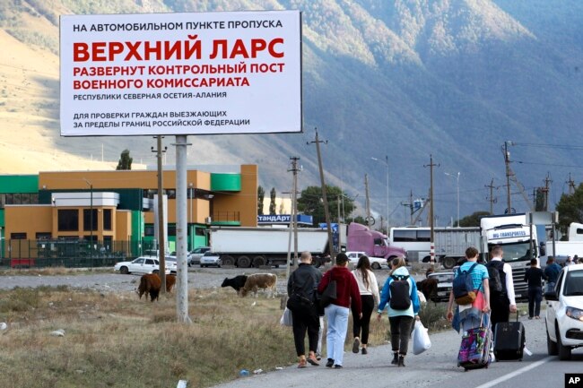 People walk toward the border crossing at Verkhny Lars between Georgia, and Russia Wednesday, Sept. 28, 2022. (AP Photo)