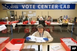 FILE - Election worker Donna Young inspects a mail-in ballot for damage at the Sacramento County Registrar of Voters in Sacramento, Calif., June 3, 2022.