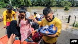 People affected by floods after the passage of Tropical Storm Julia, arrive at safe place after being evacuated by boat, in the municipality of Choloma, department of Cortes, Honduras, Oct. 10, 2022.