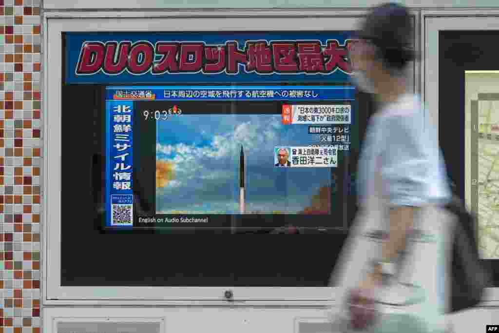 A woman walks past a public television screen in Tokyo, displaying file footage of North Korean missile launches during a broadcast about an early morning North Korean missile launch which prompted an evacuation alert when it flew over northeastern Japan.