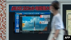 A woman walks past a public television screen in Tokyo, displaying file footage of North Korean missile launches during a broadcast about an early morning North Korean missile launch which prompted an evacuation alert when it flew over northeastern Japan.