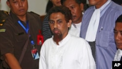 Hisyam bin Alizein, tengah, yang lebih dikenal dengan alias Umar Patek, pembuat bom bom Bali 2002, dikawal oleh jaksa dan polisi berpakaian preman saat meninggalkan ruang sidang setelah sidang di Pengadilan Negeri Jakarta Barat di Jakarta , pada 21 Mei 2012. (Foto: AP)