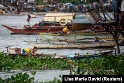 Para pria mengamankan perahu mereka setelah hujan deras yang dibawa oleh Badai Tropis Nalgae (Paeng) di Manila, Filipina, 29 Oktober 2022. (Photo: REUTERS/Lisa Marie David)