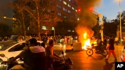 FILE - In this photo taken Sept. 19, 2022, and obtained by the AP outside Iran, a police motorcycle and a trash bin are burning during a protest over the death of Mahsa Amini in police custody, in Tehran, Iran.
