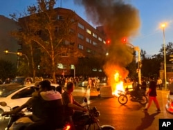 FILE - In this photo taken Sept. 19, 2022, and obtained by the AP outside Iran, a police motorcycle and a trash bin are burning during a protest over the death of Mahsa Amini in police custody, in Tehran, Iran.