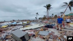 En esta captura de video proporcionado por Bobby Pratt, la gente camina por el área de Times Square en Fort Myers Beach, Florida, después de que el huracán Ian azotara el área, el jueves 29 de septiembre de 2022. (Bobby Pratt vía AP)