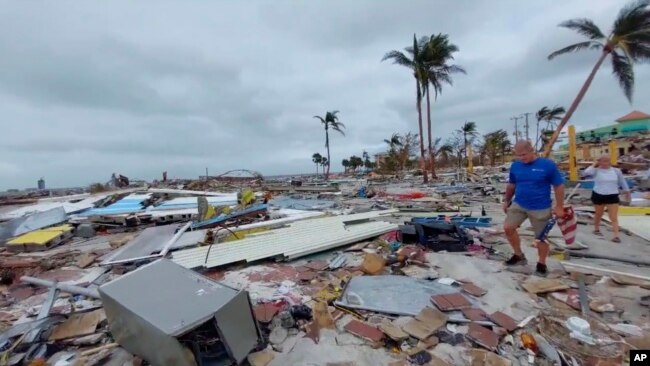 En esta captura de video proporcionado por Bobby Pratt, la gente camina por el área de Times Square en Fort Myers Beach, Florida, después de que el huracán Ian azotara el área, el jueves 29 de septiembre de 2022. (Bobby Pratt vía AP)