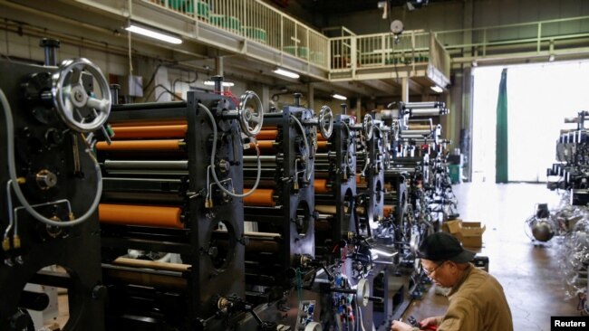 FILE - A worker checks machinery at a factory in Higashiosaka, Japan June 23, 2022.