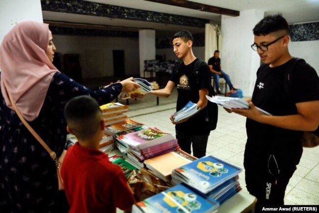 Schoolboys collect unedited textbooks as part of a protest in East Jerusalem October 1, 2022. (REUTERS/Ammar Awad)