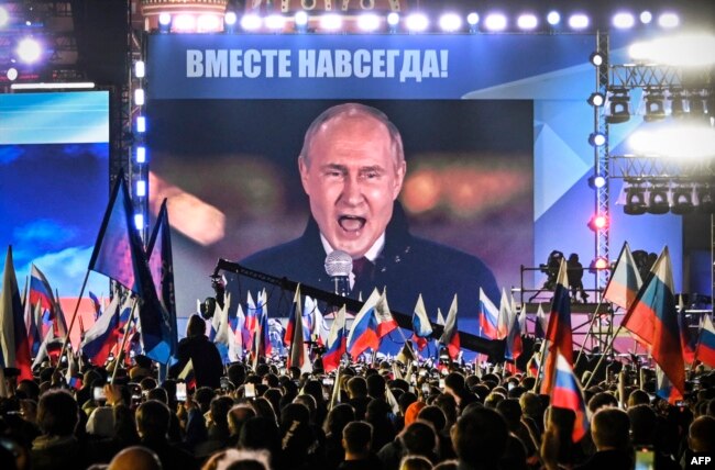 Russian President Vladimir Putin is seen on a screen in Red Square as he addresses a rally marking the annexation of four regions of Ukraine Russian troops occupy, in Moscow Sept. 30, 2022. The words above him read "Forever together." (Photo by Alexander NEMENOV / AFP)