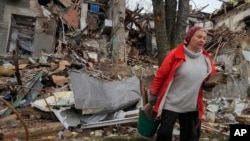Local resident Nina, 72, carries wooden debris near her home, ruined by Russian shelling a month ago, in central Slovyansk, Donetsk region, Ukraine, Oct. 29, 2022. She keeps living in the ruins of her home and collects wood to make an outdoor fire for cooking.