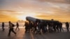 Migrants carry a smuggling boat on their shoulders as they prepare to embark on the beach of Gravelines, near Dunkirk, northern France, Oct. 12, 2022, in a attempt to cross the English Channel.