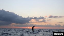 FILE - A standup paddle boarder is seen in waters between Cyprus and Lebanon, near Cape Greco Peninsula, Cyprus, Oct. 16, 2020. Both countries are locked in a dispute over their maritime border.