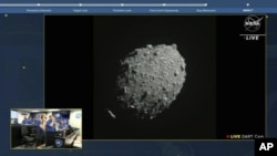 26일 미 항공우주국(NASA)의 '다트' 우주선이 충돌 몇 분전에 찍어온 '다이모르포스' 소행성의 사진을 상황실 근무자들이 실시간으로 지켜보고 있다.