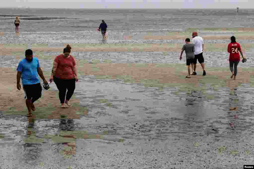 Los residentes locales caminan sobre la arena mientras el agua se retira de la bahía de Tampa antes del huracán Ian en Tampa, Florida, el 28 de septiembre de 2022.