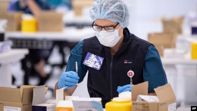 FILE - A technician prepares a Pfizer vaccine at a COVID-19 vaccination site in Sydney, Australia, May 10, 2021.
