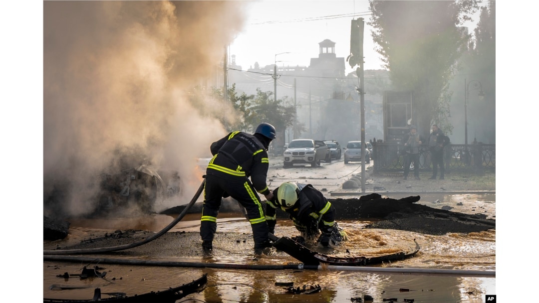 Seorang petugas pemadam kebakaran membantu rekannya melarikan diri dari kawah setelah serangan Rusia di Kyiv, Ukraina, 10 Oktober 2022. (Foto: AP)