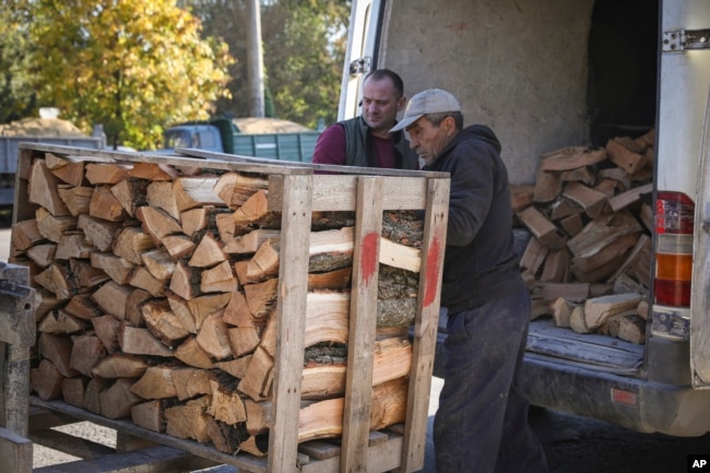 People load firewood from a pallet into a van outside Chisinau, Moldova, Saturday, Oct. 15, 2022. (AP Photo/Aurel Obreja)